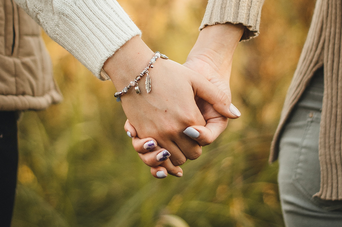 Close up cropped photo of two people holding hands