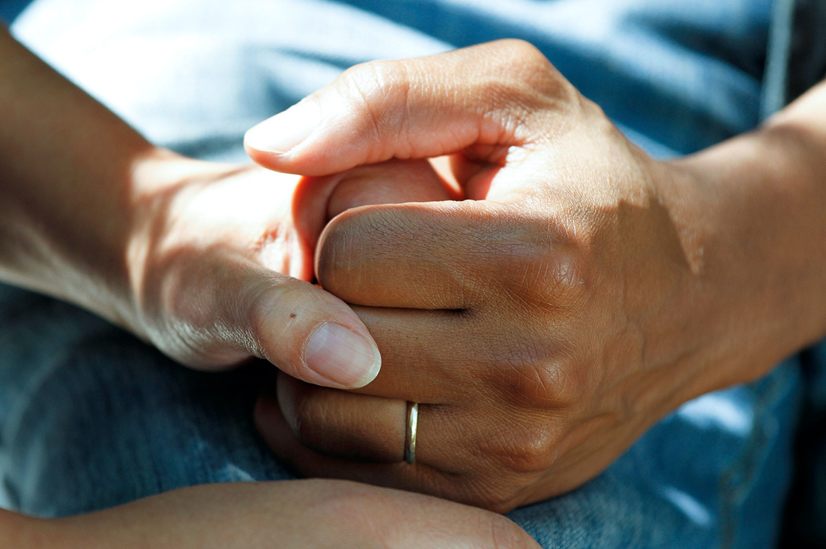 Two people holding hands, sitting together.