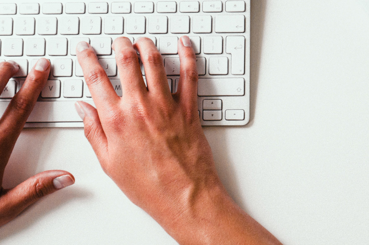 Person typing on a computer keyboard.